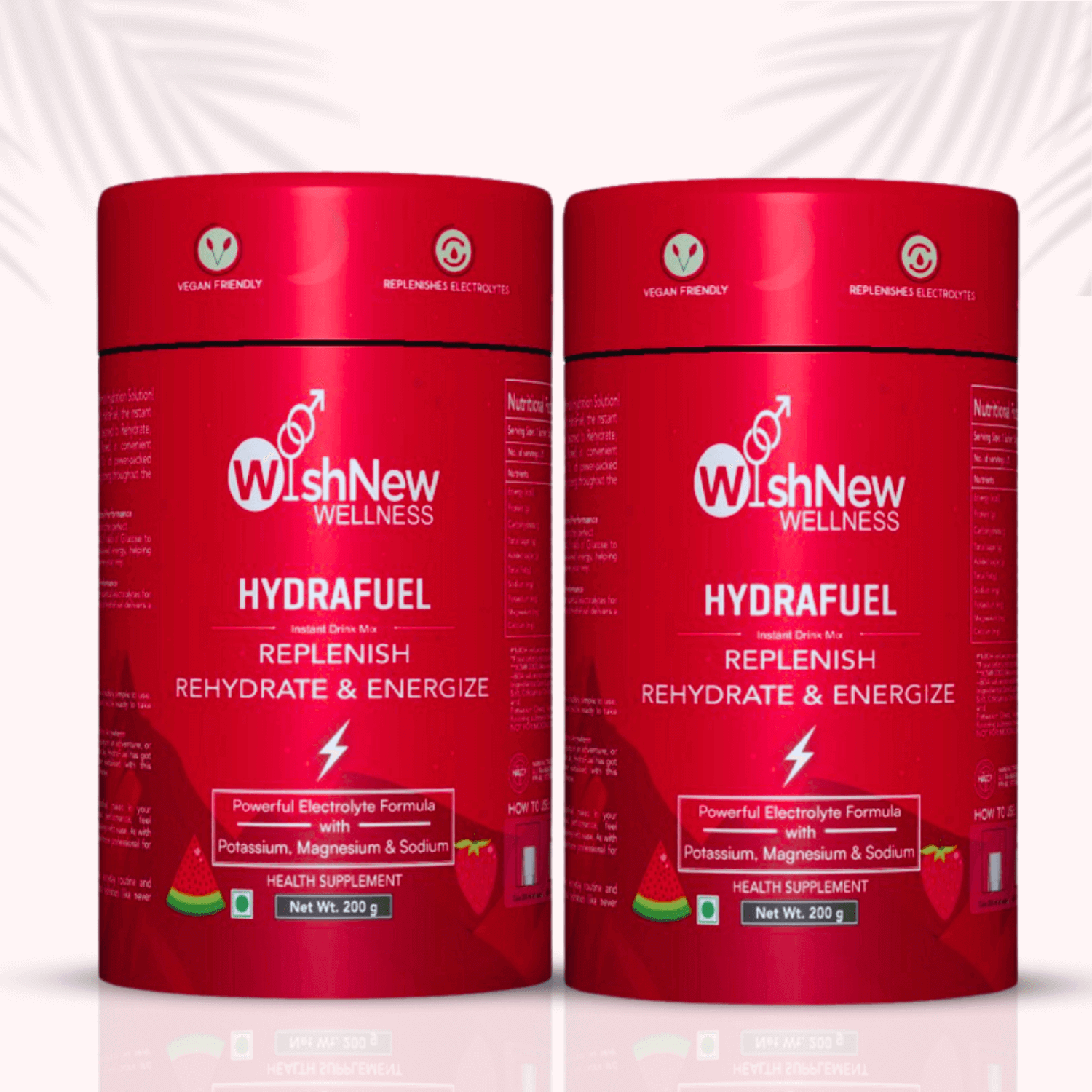 Product image featuring two containers of WishNew Wellness Hydrafuel placed side by side. Both bright red canisters are labeled "Hydrafuel – Replenish, Rehydrate & Energize" and highlight a powerful electrolyte formula with potassium, magnesium, and sodium. Icons above the label indicate the product is vegan friendly and replenishes electrolytes. Light background with subtle palm leaf shadows.